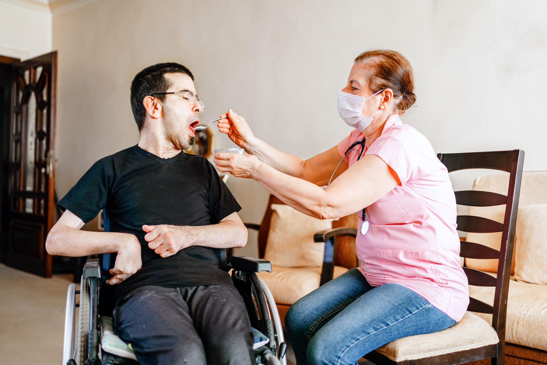 Serious disabled young man at home with nurse